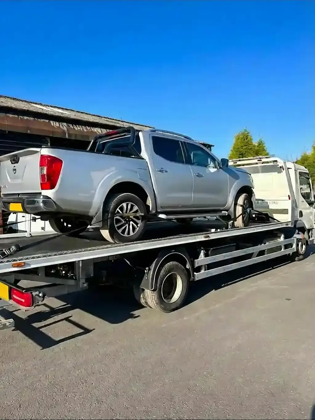 Silver Nissan Navara pickup truck on flatbed recovery vehicle. Premier Recoveries provides professional 4x4 and pickup truck recovery services throughout the UK.