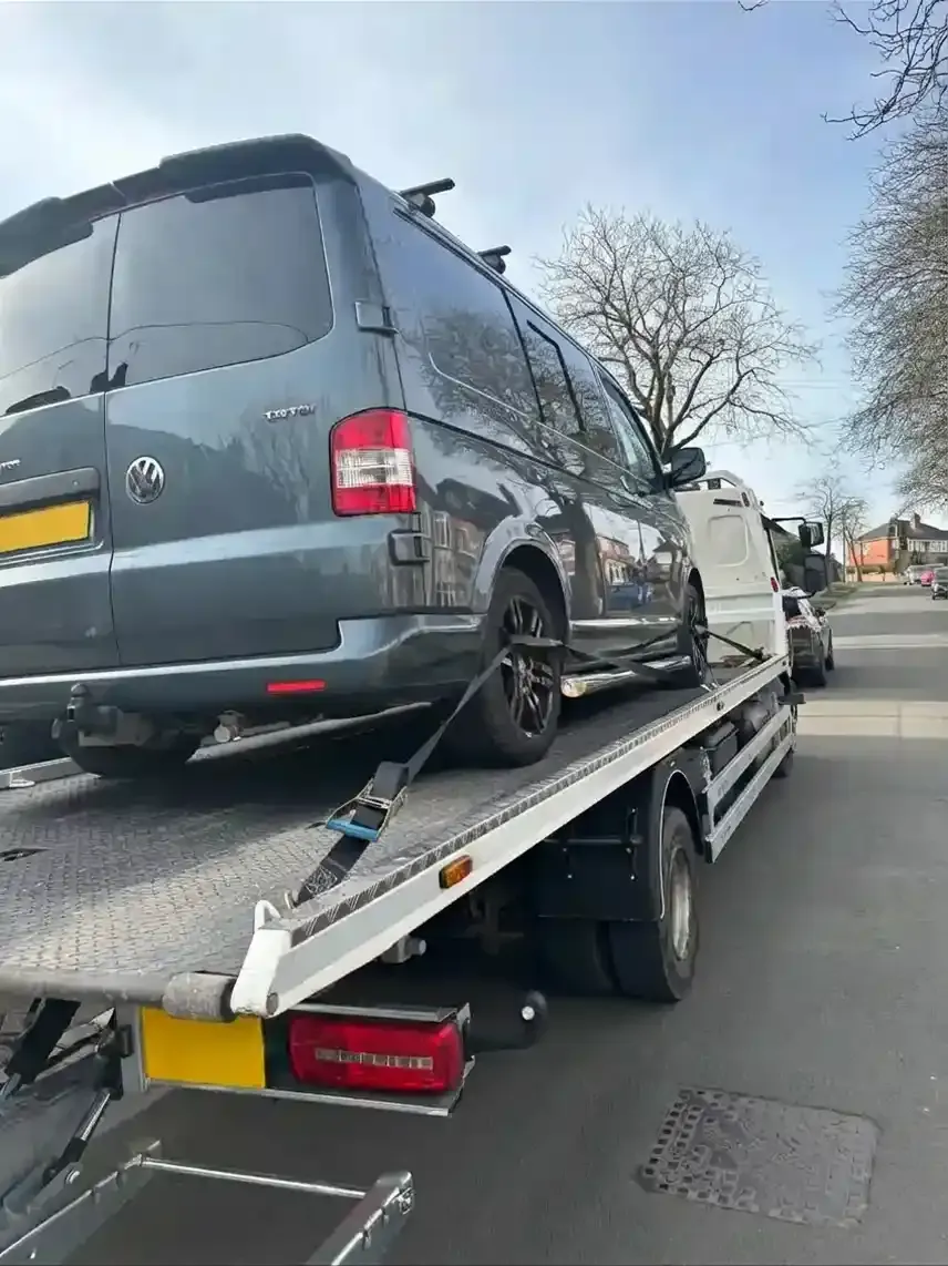 Dark grey VW Transporter van being transported on a professional flatbed recovery truck. Premier Recoveries specialises in van recovery and breakdown services throughout the UK.